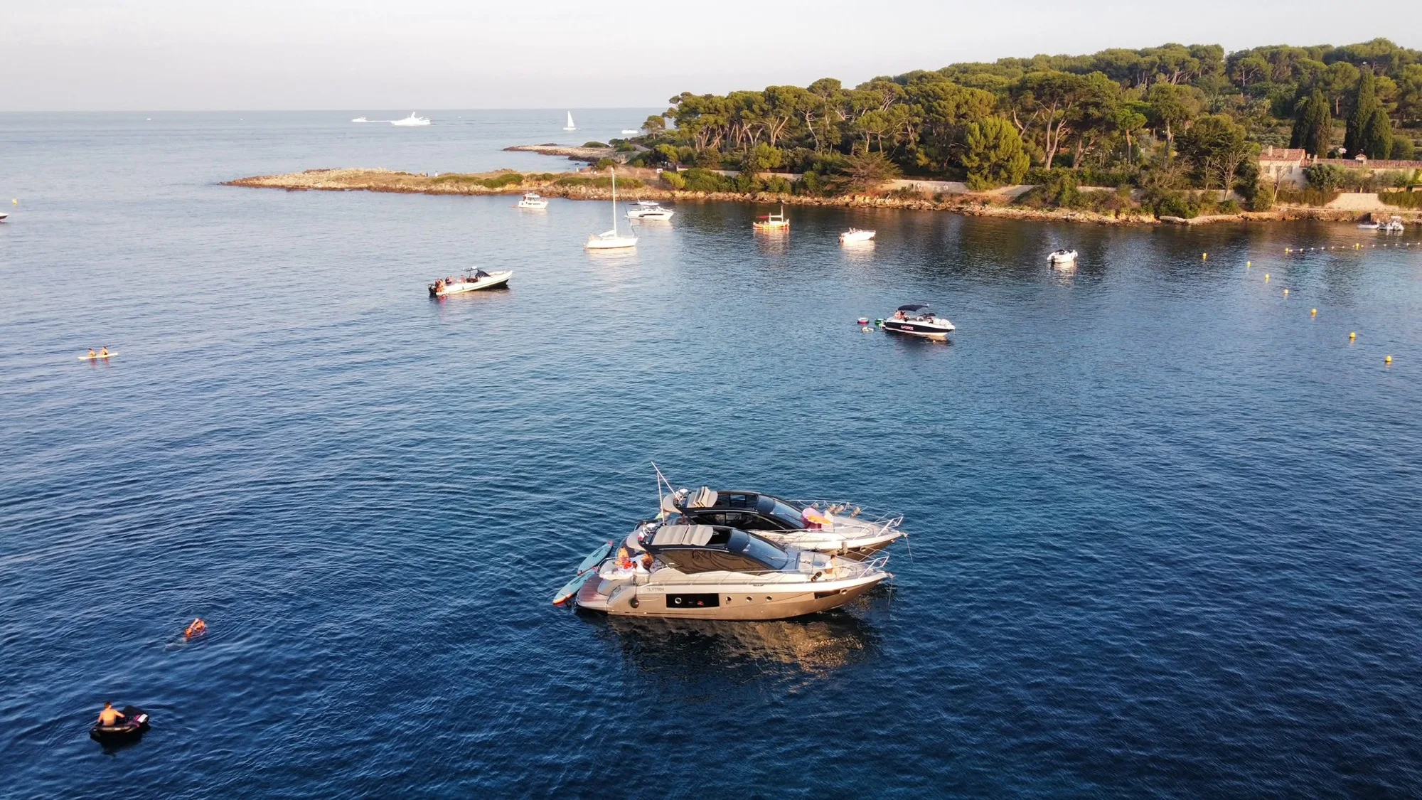 Two of the fleet rafted together at anchor off the Lérins, guests swimming around them.
