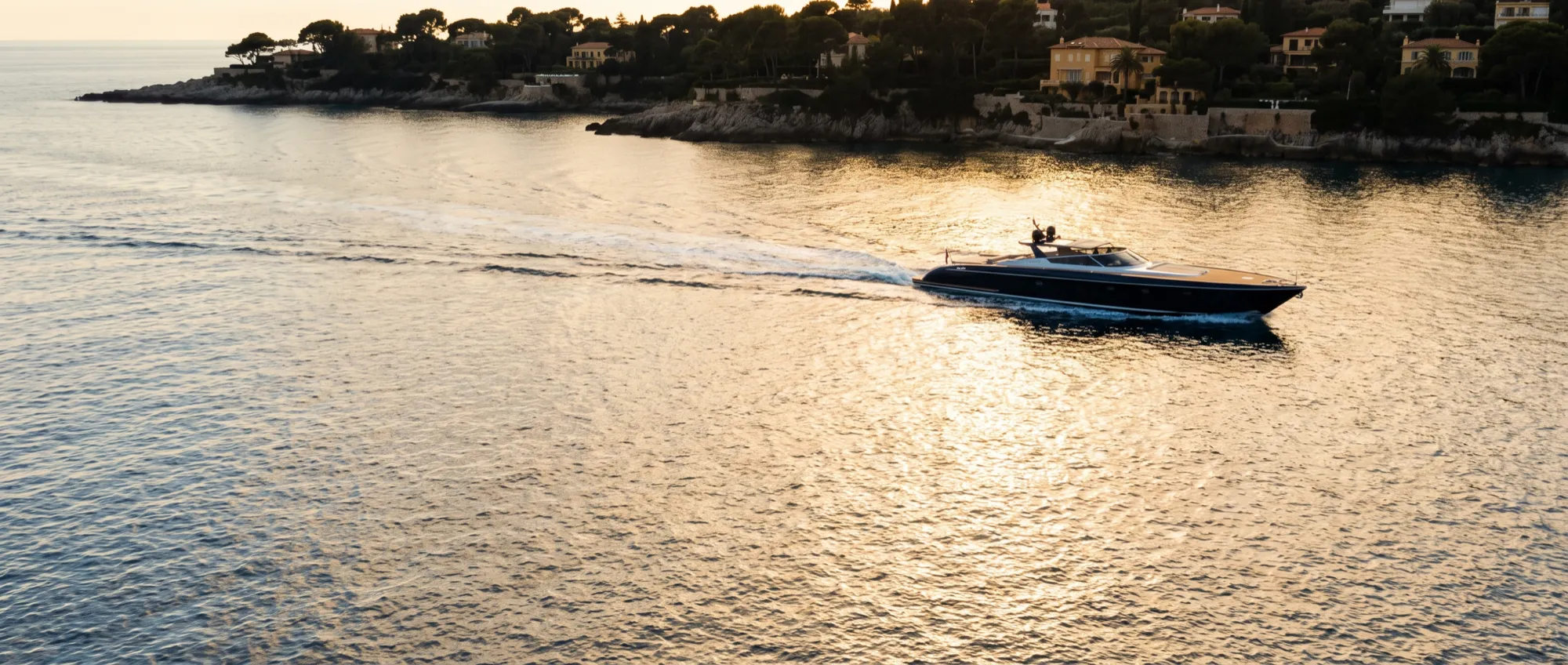 Un bateau à la journée rentrant le long de la côte dans la lumière dorée.