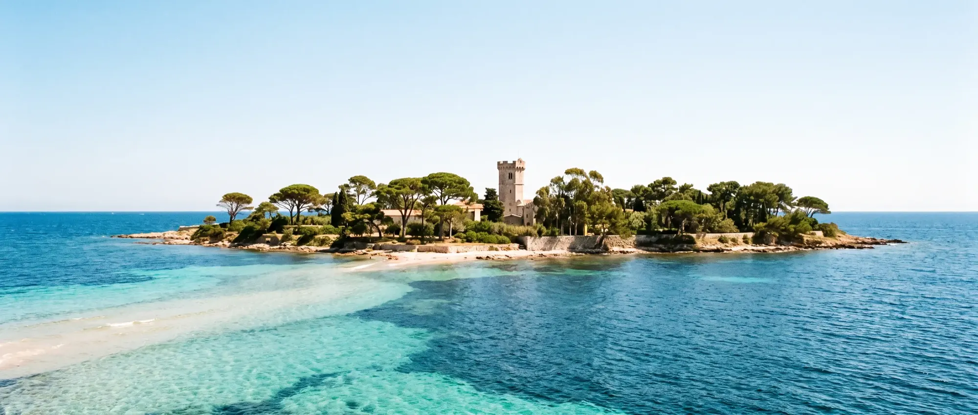 Une eau turquoise en bandes sur le sable, entre les îles boisées de Lérins.