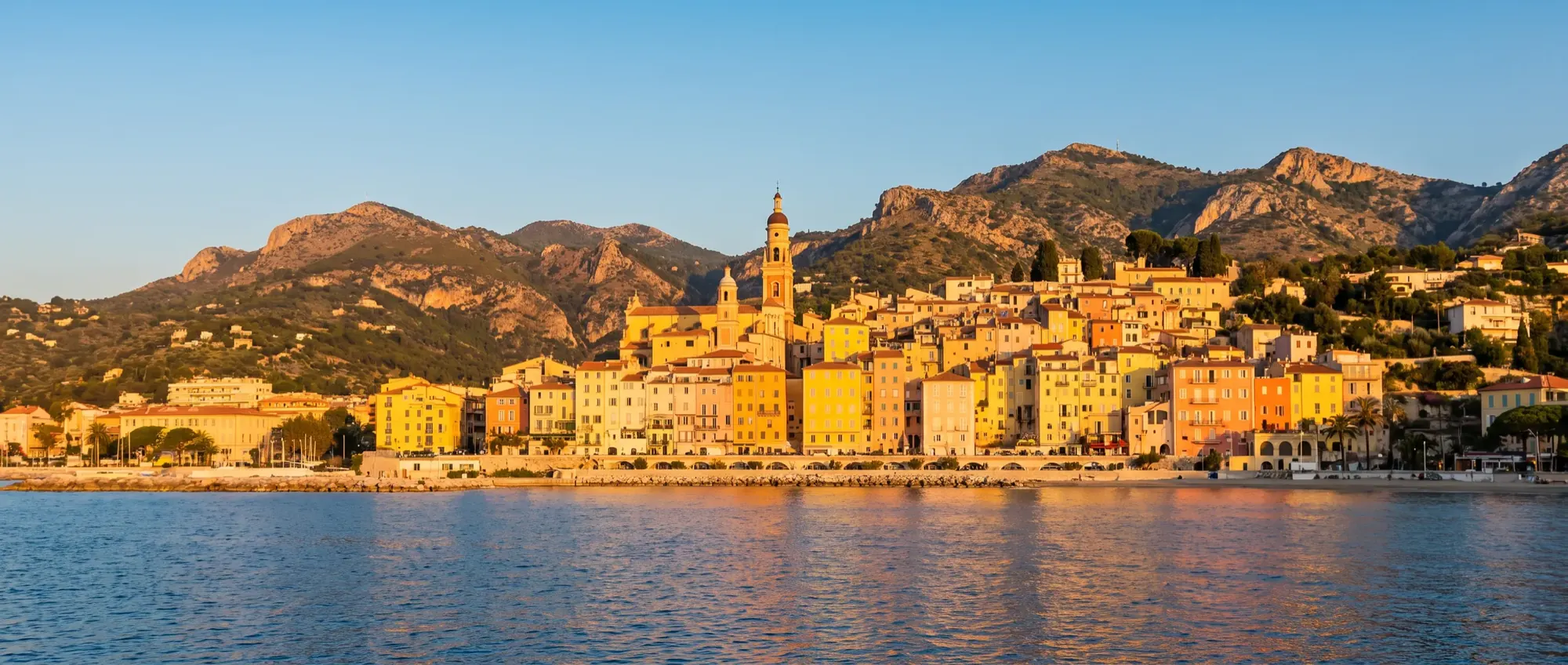 Les façades citron et abricot de la vieille ville de Menton vues depuis la mer.