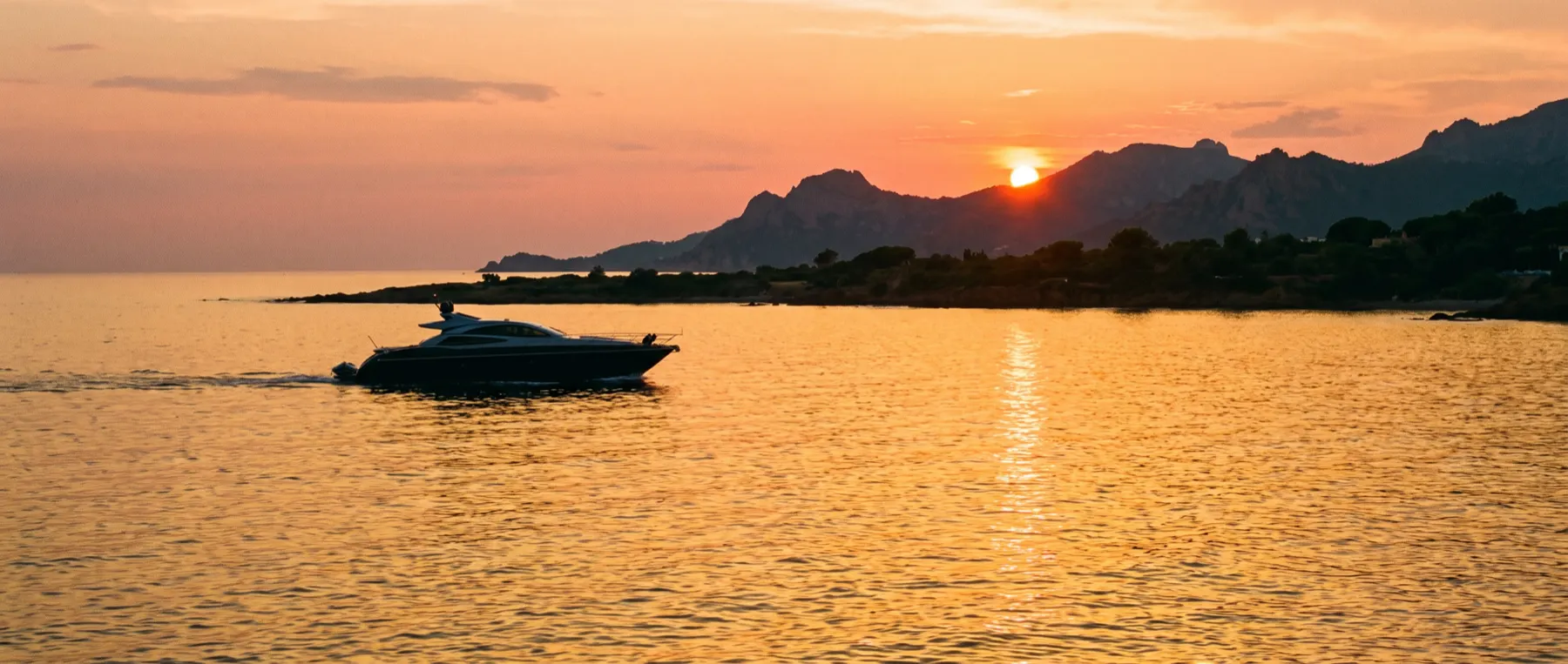 The wake of a boat running home along the coast at sunset.