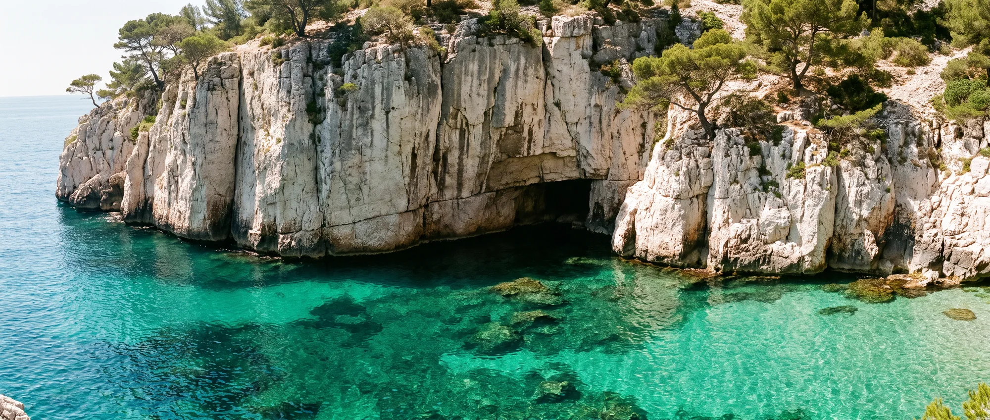 White cliffs dropping straight into emerald water in a narrow calanque.