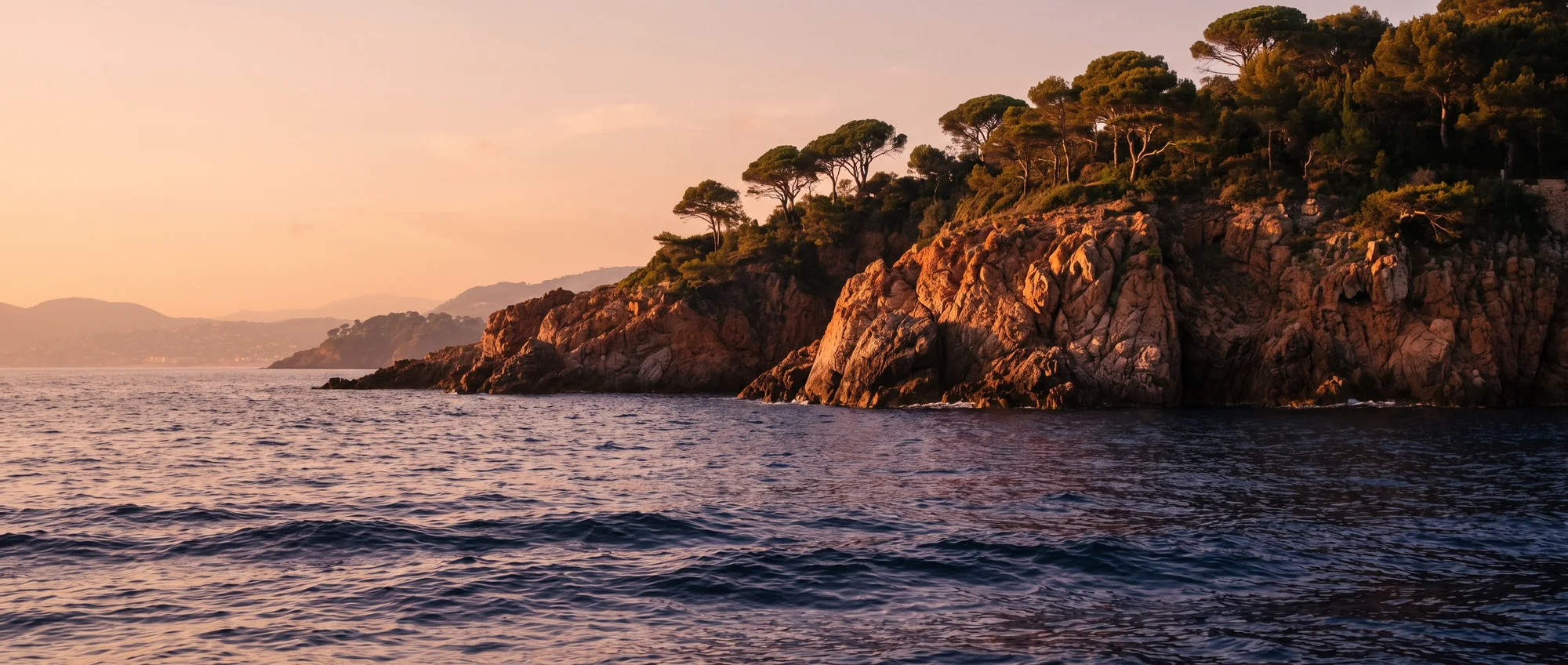 A rocky headland going dark against the last of the light on the water.